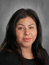 Headshot of a woman with long dark hair and a black top, smiling softly against a gray background.