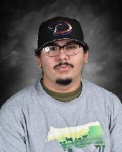 A young man with glasses and a baseball cap poses for a portrait against a dark background.