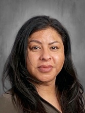 A woman with long black hair, wearing a neutral-colored top, smiles against a gray background.